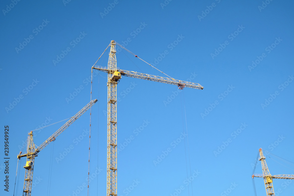 Big yellow construction tower crane over clear blue as background, sky horizontal photo Big yellow construction tower crane over clear blue as background, sky horizontal photo