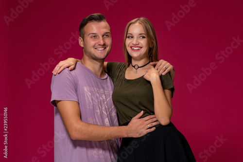 Young nice couple posing in the studio, express emotions and gestures, smiling, on a burgundy background © nazarovsergey