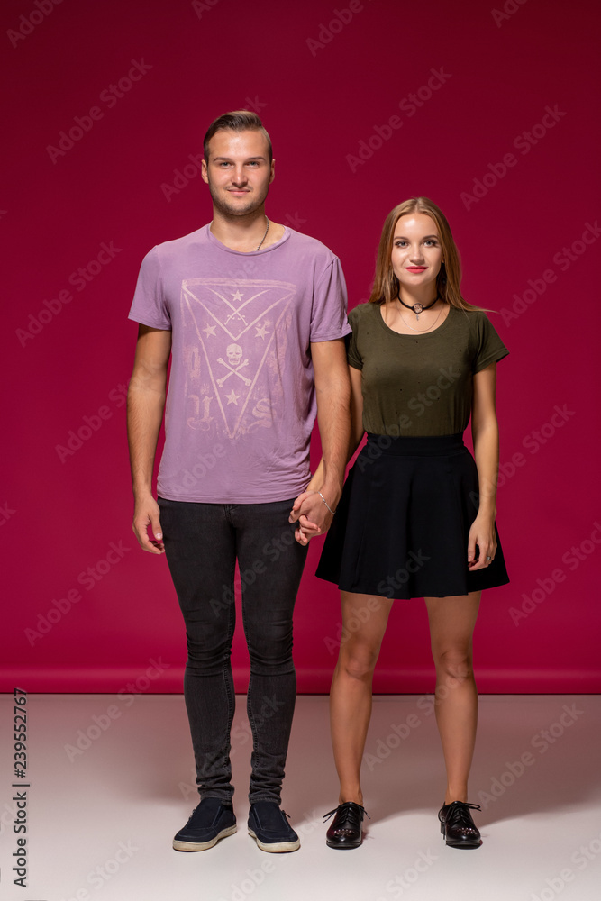 Totally in love. Full length of beautiful young couple embracing and smiling while standing against burgundy background Totally in love. Full length of beautiful young couple embracing and smiling while standing against burgundy background