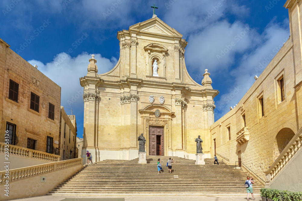 Gozo, Malta - May 16th 2019 - Tourist and locals walking in front of a catholic church in Gozo, northern of Malta