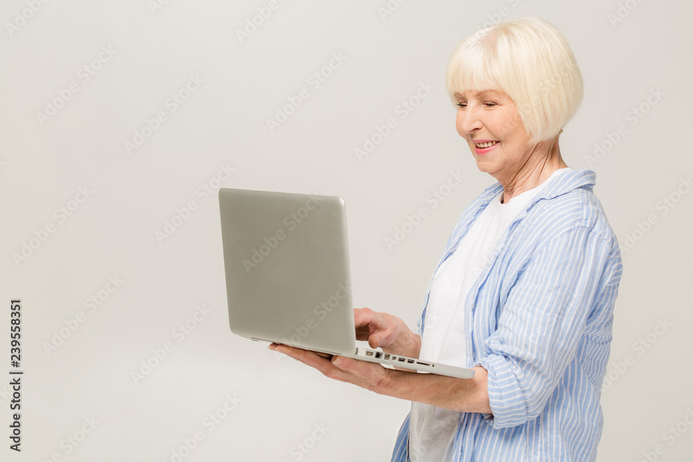 Happy senior woman standing with laptop, isolated on white background Happy senior woman standing with laptop, isolated on white background
