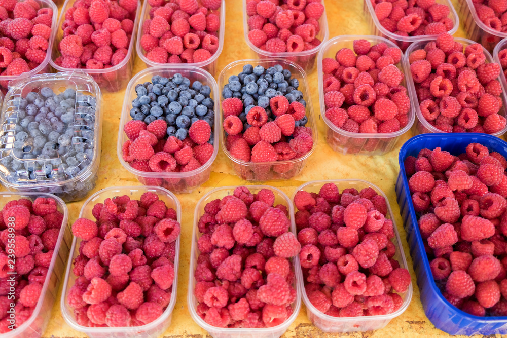 Raspberries and blueberries in plastic transparent boxes sold at Ljubljana central market. Slovenia