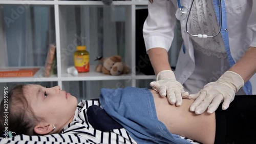Pediatrician doing abdominal examination with hands.Doctor checking stomach of sick girl