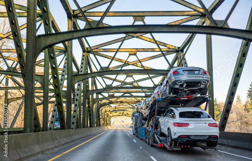 Canvas Print Big rig car hauler semi truck transporting cars on the trailer and driving on th