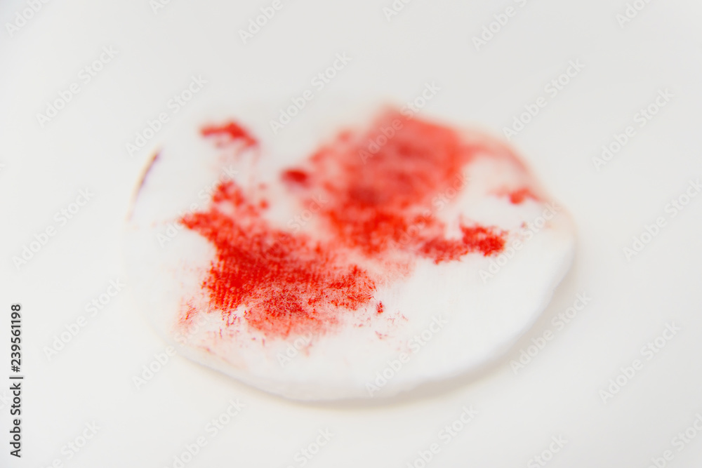Cotton disc with blood. Cotton disc with traces of red blood. Old dried  blood on cotton sponge. Blood stains after a cut. Bloody cotton swab on a  white background. Stock Photo