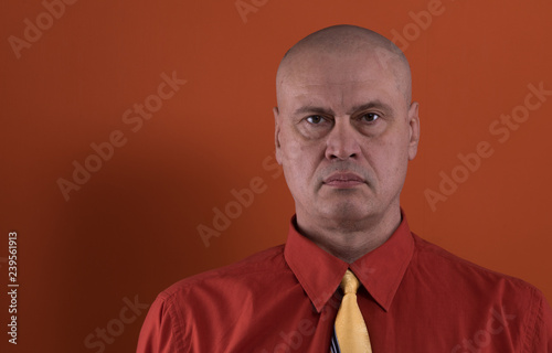 studio portrait of a bald man on a red background