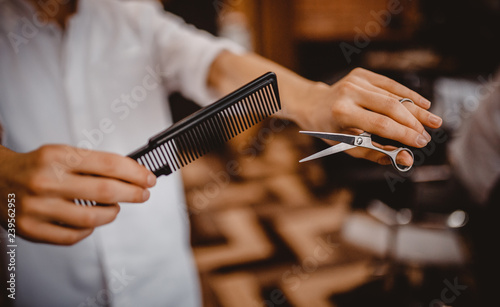 Close-up  Barber holding scissors and comb  background is blurred. Concept of men style