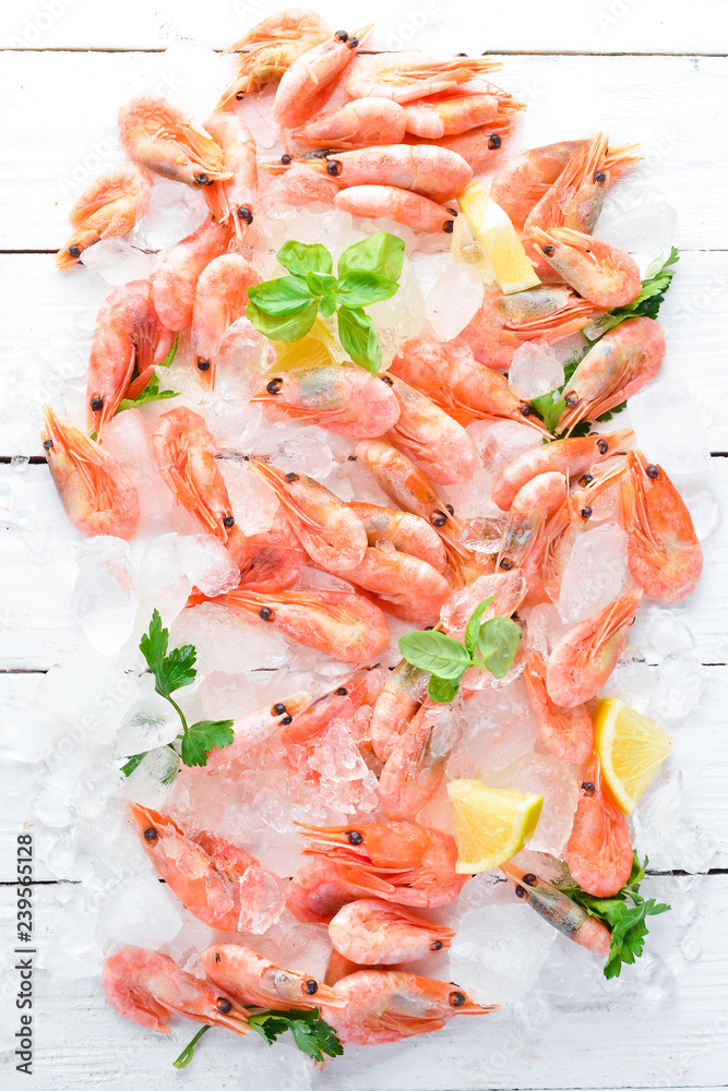 Shrimp with ice and lemon. Seafood. On a white wooden background. Top view. Free copy space.