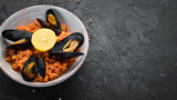 Bulgur with mussels and tomato sauce in a plate. On the old background. Top view. Free space for your text.