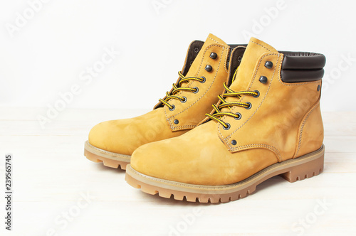 Yellow men's work boots from natural nubuck leather on wooden white background. Trendy casual shoes, youth style. Concept of advertising autumn winter shoes, sale, shop.