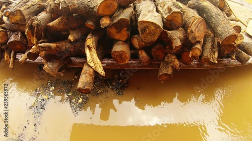 Big firewood on boat black coals float in brown water cremation ghat Manikarnika photo