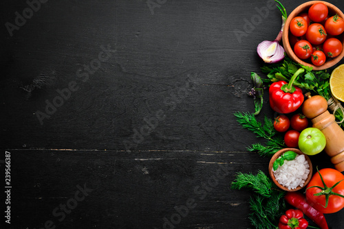 Vegetable background. Fresh tomatoes  paprika  onions and parsley on the table. Top view. On a black background. Free space for text.