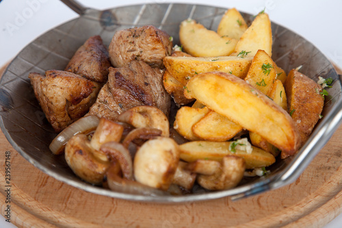 Potatoes with meat and mushrooms in the iron plate