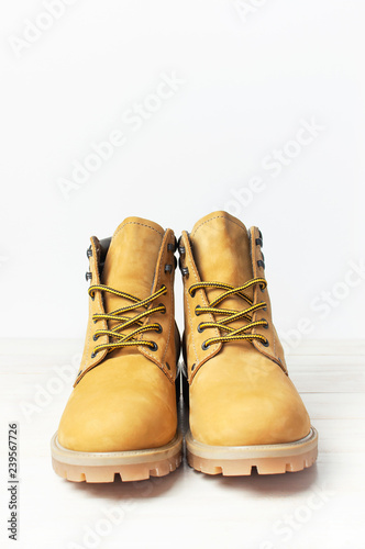 Yellow men's work boots from natural nubuck leather on wooden white background. Trendy casual shoes, youth style. Concept of advertising autumn winter shoes, sale, shop.