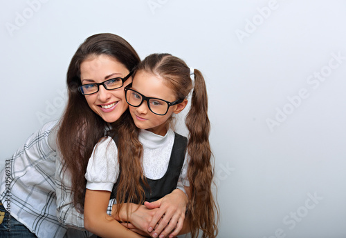 Happy young mother and kid girl in fashion glasses hugging on empty copy space background.