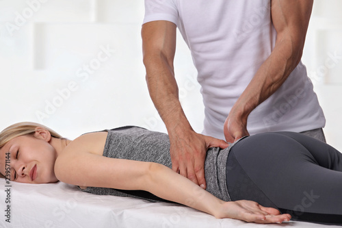 Woman having chiropractic back adjustment. Osteopathy, Physiotherapy, sport injury rehabilitation concept, holistic care