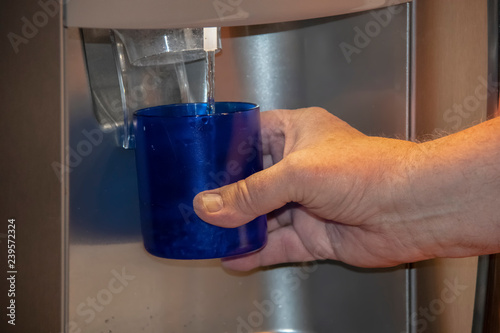 Fotografija Man holding class under water dispenser in refrigerator door - close-up cropped