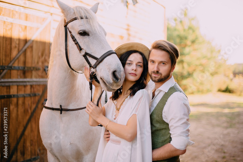 stylish newlyweds stand near horse and look into camera © MZaitsev