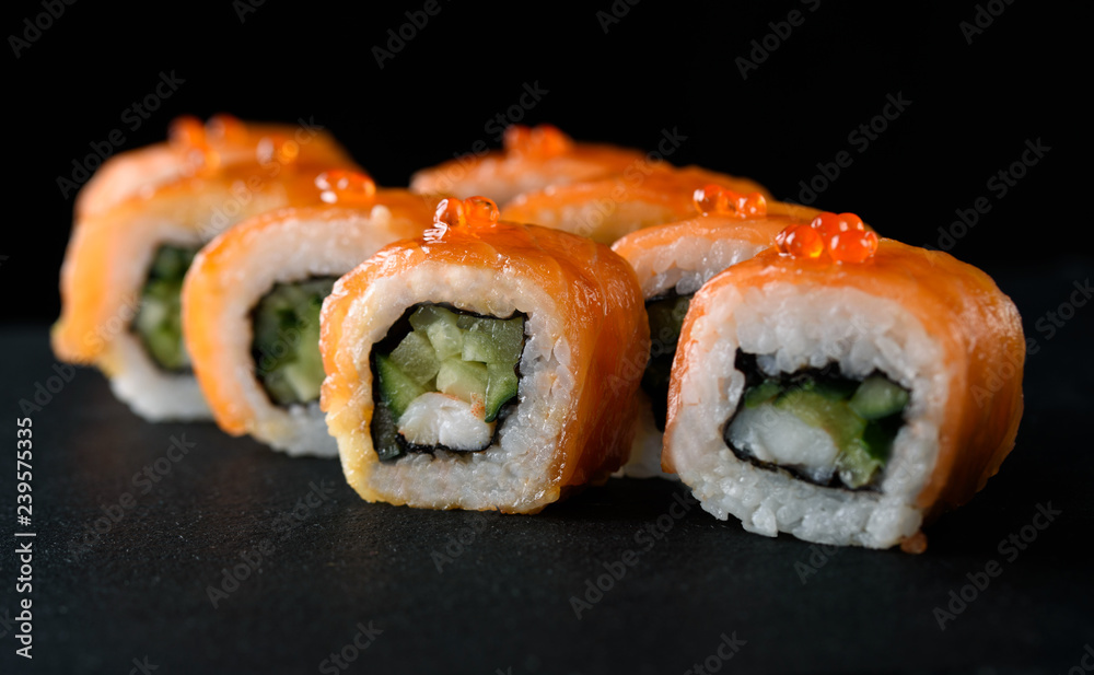 Delicious and appetizing sushi with red fish on black acrylic with reflection. Sushi close up. Delicious and appetizing sushi with red fish on black acrylic with reflection. Sushi close up.