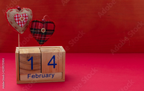Valentines day. 14 February and two red fabric hearts on red background.