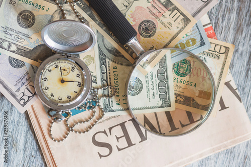 Pocket clock, American dollars and a magnifying glass