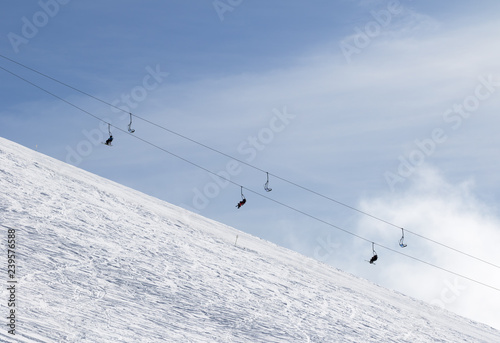 Snowy off-piste ski slope with traces from skis and snowboards and chair-lift