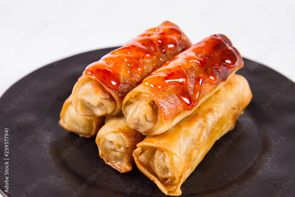 Chinese Traditional Spring rolls with sweet and sour sauce on a black plate Chinese Traditional Spring rolls with sweet and sour sauce on a black plate