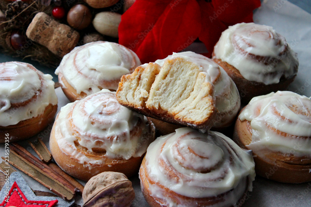 Cinnamon rolls for Christmas. Christmas cakes. Buns in glaze on a wooden table, scattered nuts and cinnamon sticks, rustic style. Homemade cake. Christmas background. Greeting card.