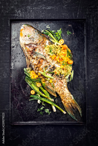 Traditional BBQ parrotfish with mango salsa as top view on a black board