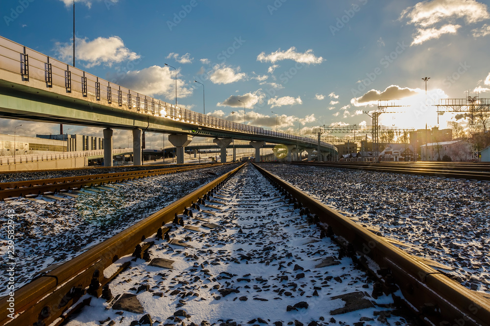 Fototapeta premium Deserted railway tracks leading to the horizon and intersecting overpasses