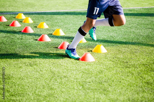 Soccer player Jogging and jump between cone markers on green artificial turf for soccer training