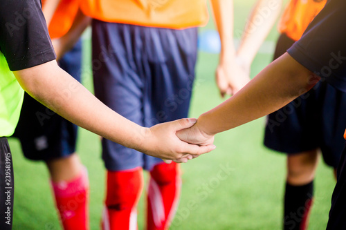 Young boy soccer players tap hands together for football training