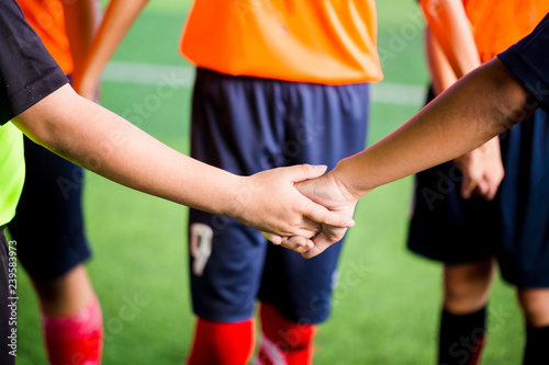 Young boy soccer players tap hands together for football training