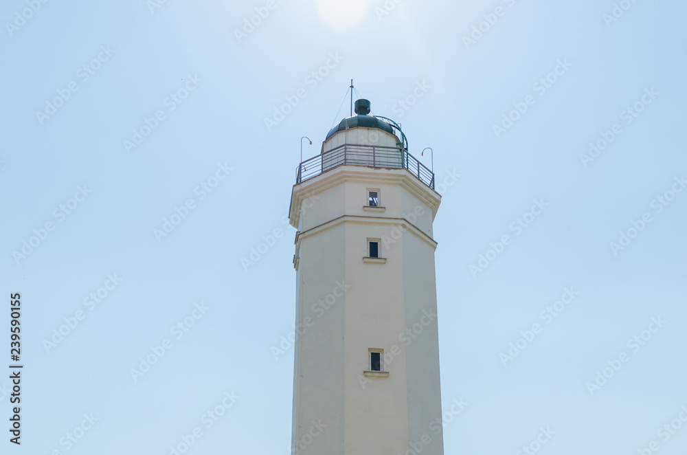 White lighthouse against the blue sky on a sunny day