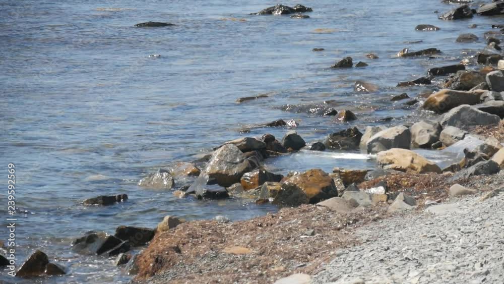 Front view of sea waves breaking on rocks. Rock with the big stones in the sea and waves with foam. Front view of sea waves breaking on rocks. Rock with the big stones in the sea and waves with foam.