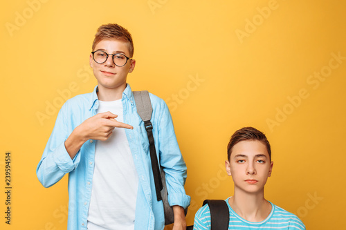 Two teenage friends, one guy humiliates the other, popular humiliates the unpopular, on a yellow background photo