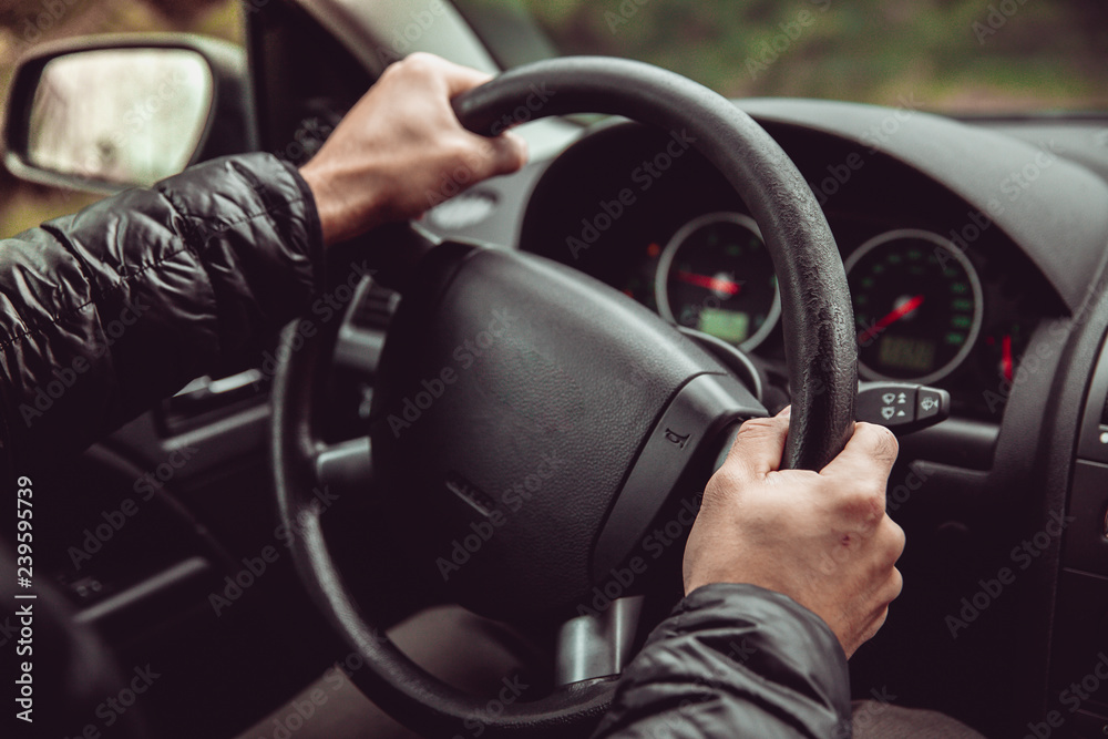 a driver in a car performs tasks necessary to steer the vehicle