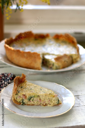 Slice of homemade quiche filled with cheese, ham and leek. Selective focus.
