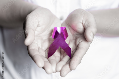 Womans hands holding purple domestic violence awareness ribbon, healthcare and social problems concept.