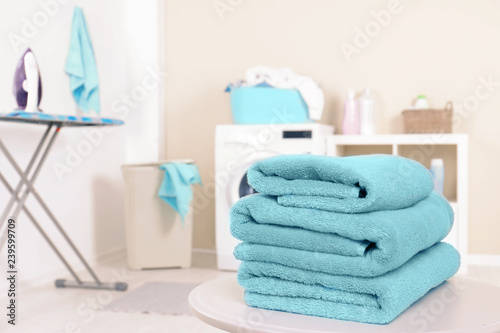 Stack of clean towels on table in laundry room. Space for text