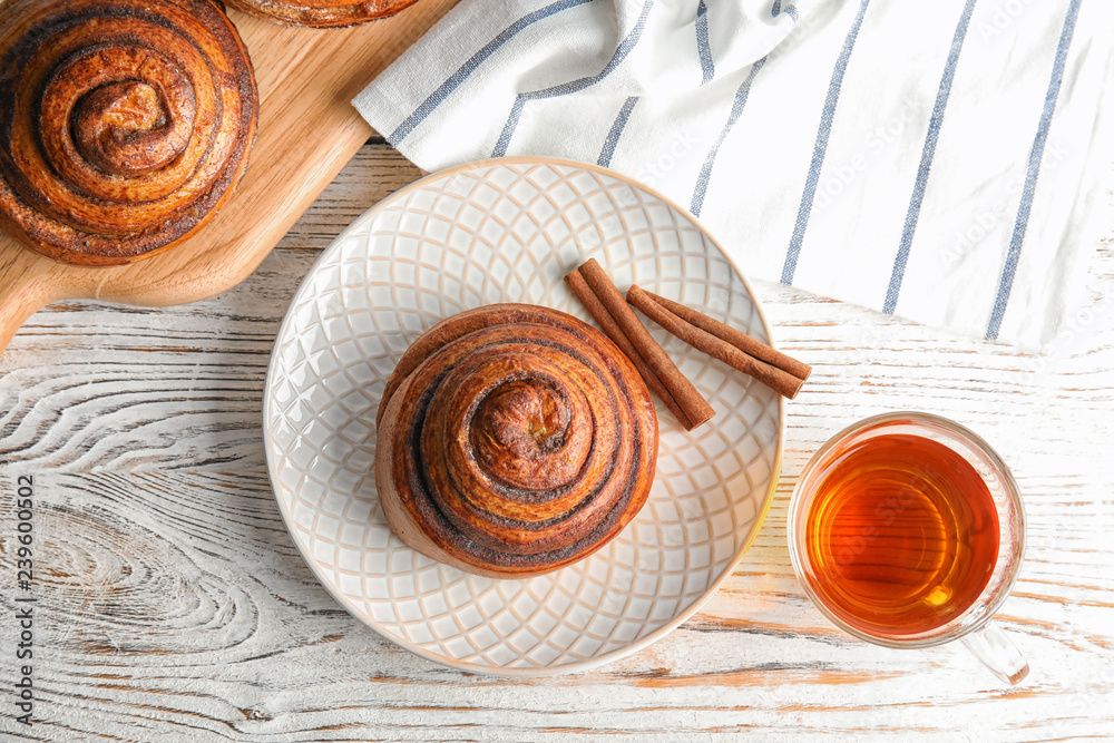 Flat lay composition with freshly baked cinnamon roll on white wooden background Flat lay composition with freshly baked cinnamon roll on white wooden background