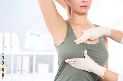 Doctor checking woman's breast at hospital, closeup. Space for text photo