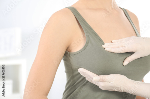 Doctor checking woman's breast at hospital, closeup