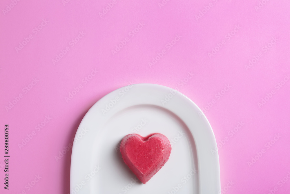 Plate with heart shaped berry ice cube on color background, top view. Space for text