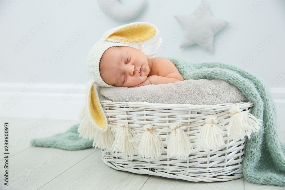 Obraz premium Adorable newborn child wearing bunny ears hat in baby nest indoors