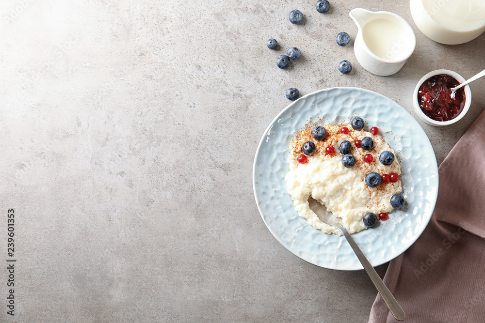 Creamy rice pudding with red currant and blueberries in bowl served on grey table, top view. Space for text Creamy rice pudding with red currant and blueberries in bowl served on grey table, top view. Space for text