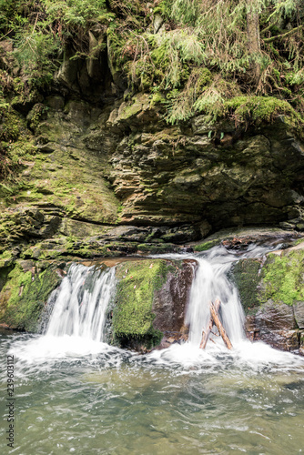 Small mountain waterfall on the rocks covered with moss in the forest