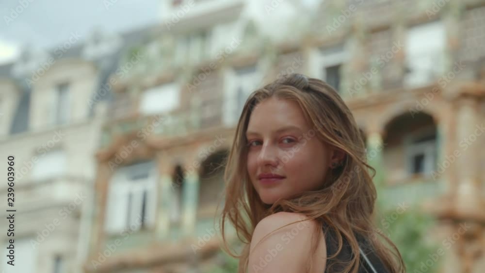 Portrait of a captivating young woman looking at the camera slyly, she turns around flipping her hair and looks back toward the camera smiling Portrait of a captivating young woman looking at the camera slyly, she turns around flipping her hair and looks back toward the camera smiling