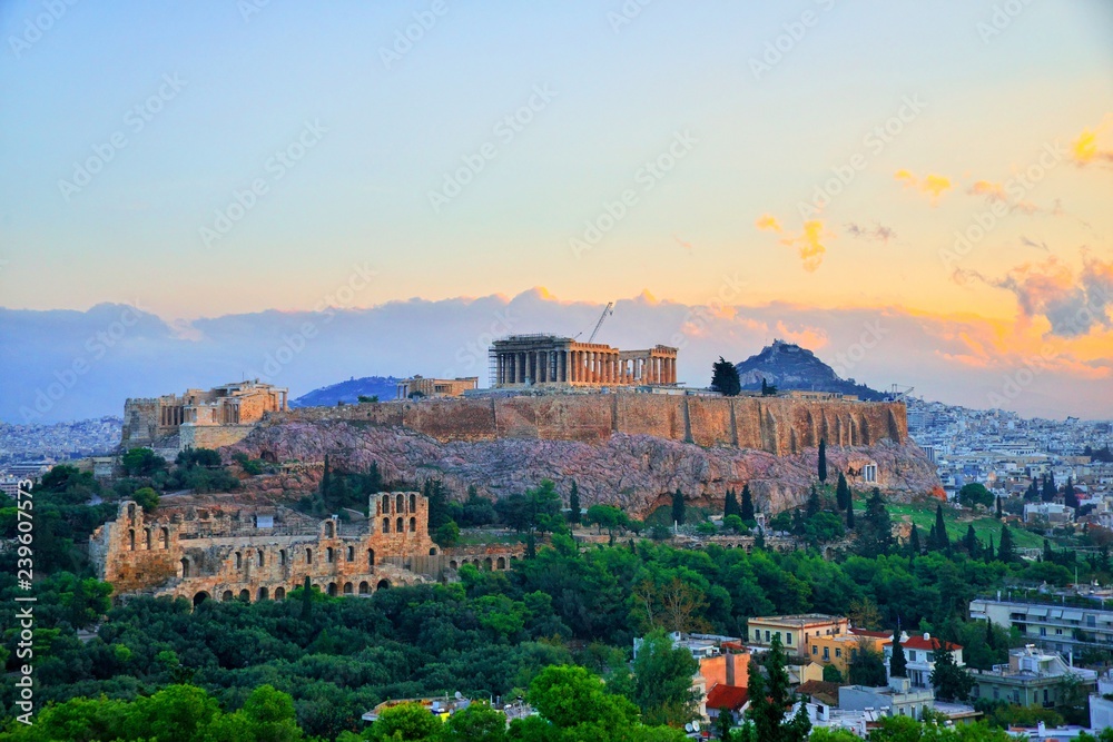 Parthenon temple in Acropolis Hill in Athens, Greece shot in blue hour over the old town during colorful sunset with pink and purple clouds in the sky