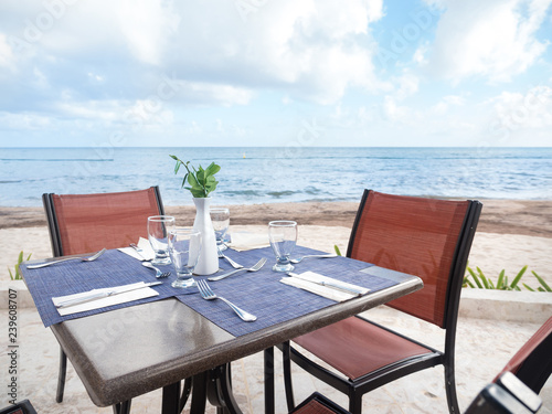 Table with dinner setting at outdoors restaurant near tropical sea